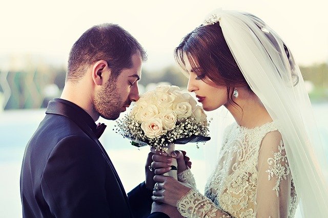 nevěsta se ženichem čichající ke svatební kytici